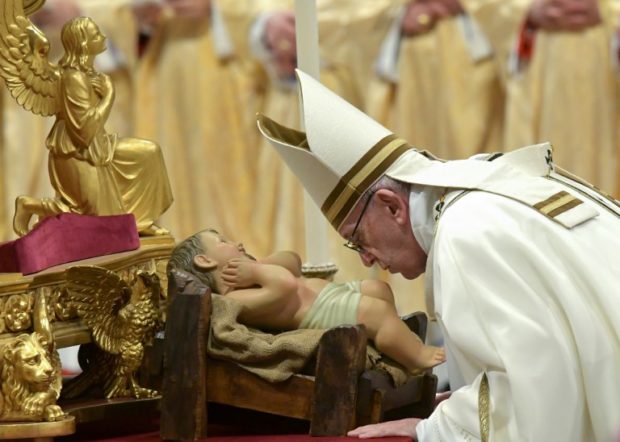 Pope Francis kisses a figurine of baby Jesus during a mass on Christmas eve on December 24, 2018 at St Peter's basilica in the Vatican. (Photo by Tiziana FABI / AFP)
