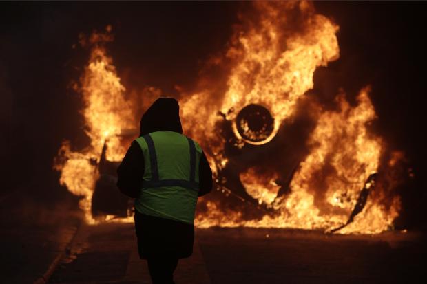 Protester watches burning car in Paris