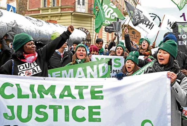 CLIMATE ACTION Carrying signs calling for a stop to the use of coal and fossil fuels, as well as for greater climate action, protesters on Saturday march from Freedom Square to Spodek Arena, where the 24th Conference of the Parties is being held, in Katowice, Poland. —AFP