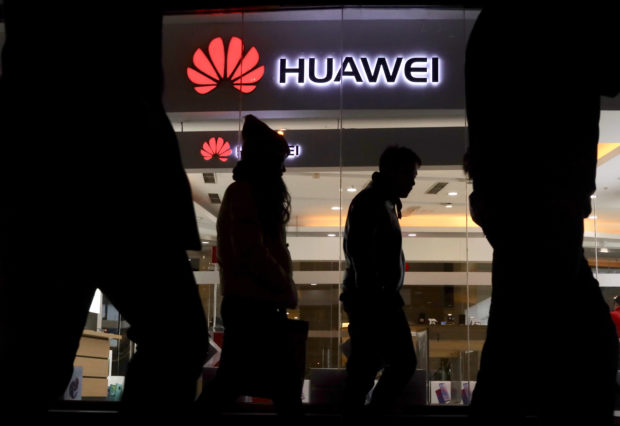 Pedestrians walk past a Huawei retail shop in Beijing Thursday, Dec. 6, 2018. China on Thursday demanded Canada release a Huawei Technologies executive who was arrested in a case that adds to technology tensions with Washington and threatens to complicate trade talks. (AP Photo/Ng Han Guan)