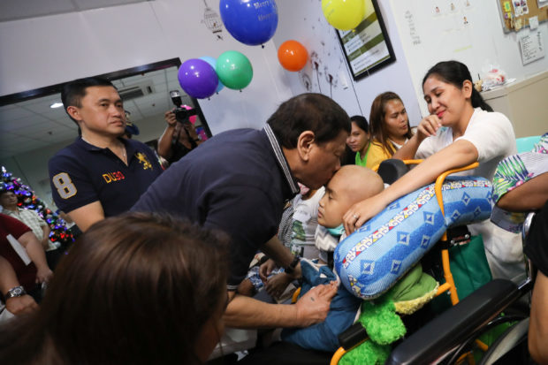 President Rodrigo Roa Duterte plants a kiss on the forehead of a pediatric patient during his visit to the Southern Philippines Medical Center's Cancer Institute Children's Unit in Davao City on December 23, 2018. Also in the photo is former Special Assistant to the President Christopher Lawrence "Bong" Go. TOTO LOZANO/PRESIDENTIAL PHOTO