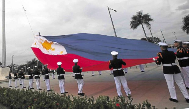HANDLE WITH CARE Soldiers raise a Philippine flag that was accidentally ripped during ceremonies for Rizal Day at the Rizal Park on Sunday. JOAN BONDOC