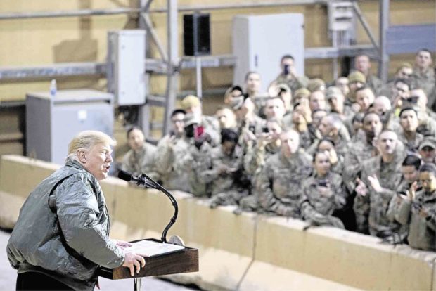 DISPUTED VISITIn a surprise trip to Iraq, US President Donald Trump speaks to the troops at a hangar of Al-Asad Air Base, west of Baghdad, on Wednesday. AP