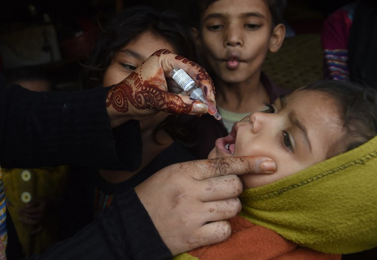 A Pakistani health worker administers polio vaccine drops to a child during a polio vaccination campaign in Lahore on December 11, 2018. - Pakistan is one of only two countries in the world where polio remains endemic. (Photo by ARIF ALI / AFP)