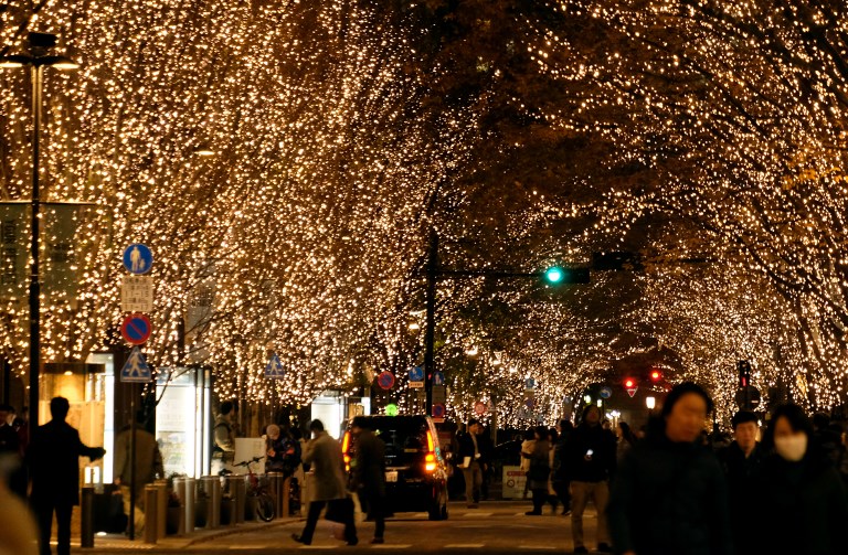 People walk under winter illuminations displayed with one million "Champagne Gold" LED bulbs at Marunouchi business district in Tokyo on December 16, 2018. (Photo by Kazuhiro NOGI / AFP)