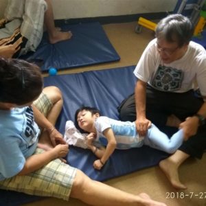 Chow (right) doing physiotherapy with a child at the Esda learning and development centre. Photo: Esda