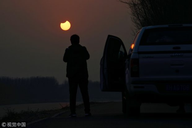 A driver stops his car to take pictures of the first solar eclipse in Beijing, on the morning of Jan 6, 2019. VCG via China Daily/Asia News Network