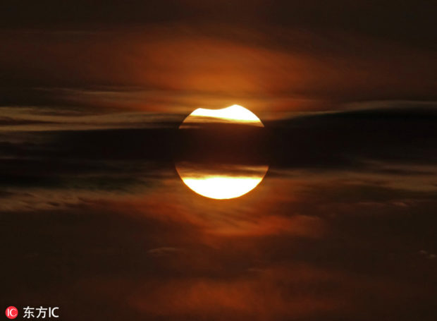 The partially eclipsed sun hides behind clouds in Dalian, Northeast China's Liaoning province, Jan 6, 2019. IC via China Daily/Asia News Network