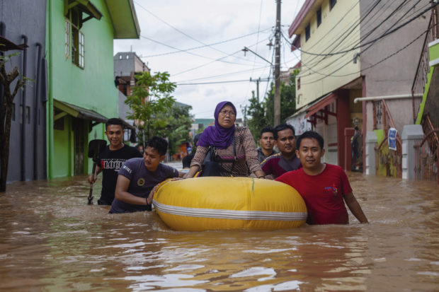 A woman sits on a rubber boat as she is evacuated from a flooded neighborhood in Makassar, South Sulawesi, Indonesia, Wednesday, Jan. 23, 2019. Torrential rains that overwhelmed a dam and caused landslides killed at least six people and displaced more than 2,000 in central Indonesia, officials said Wednesday. (AP Photo/Yusuf Wahil)