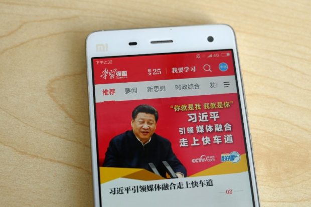 This photo illustratration taken on February 20, 2019 shows a phone app called "Xuexi Qiangguo" or "Study to make China strong" with an image of China's President Xi Jinping in Beijing. - A propaganda app that puts China's powerful President Xi Jinping in anyone's pockets has become a hit in the country -- with a helpful nudge from Communist Party officials. Xi, who could rule indefinitely after parliament lifted presidential term limits last year, has enjoyed a level of officially stoked adulation unseen since Communist China's founder Mao. (Photo by Greg Baker / AFP) / TO GO WITH China-politics-internet, FOCUS by Poornima WEERASEKARA