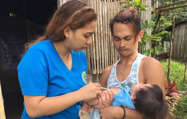 Health worker immunizing child
