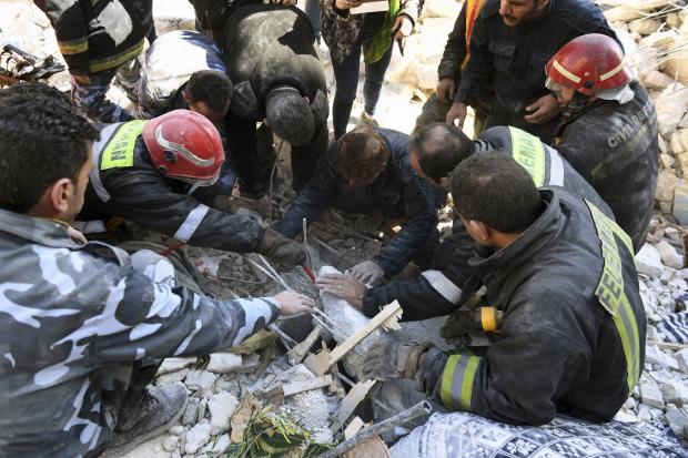Rescuers searching in rubble of collapsed building in Syria