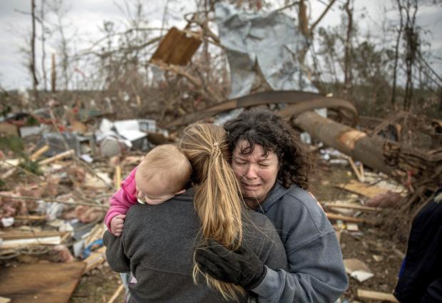 Family standing on rubble of tornado hit home