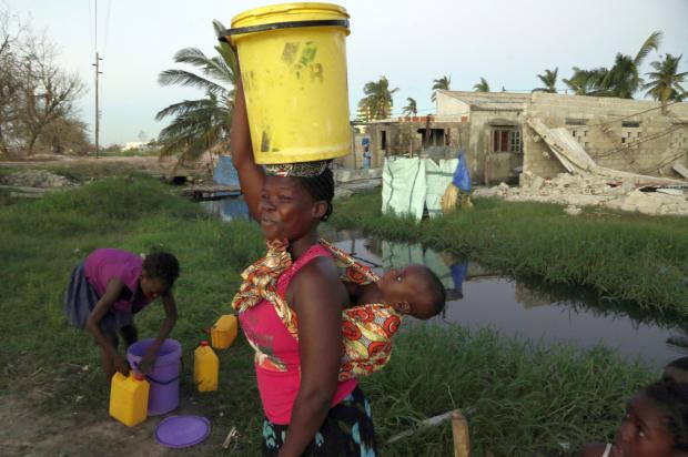 Woman with pail on head carrying baby in Mozambique