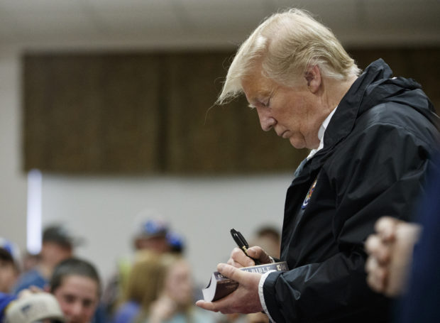 President Donald Trump signs a Bible as he greets people at Providence Baptist Church in Smiths Station, Ala., Friday, March 8, 2019, during a tour of areas where tornados killed 23 people in Lee County, Ala. (AP Photo/Carolyn Kaster)