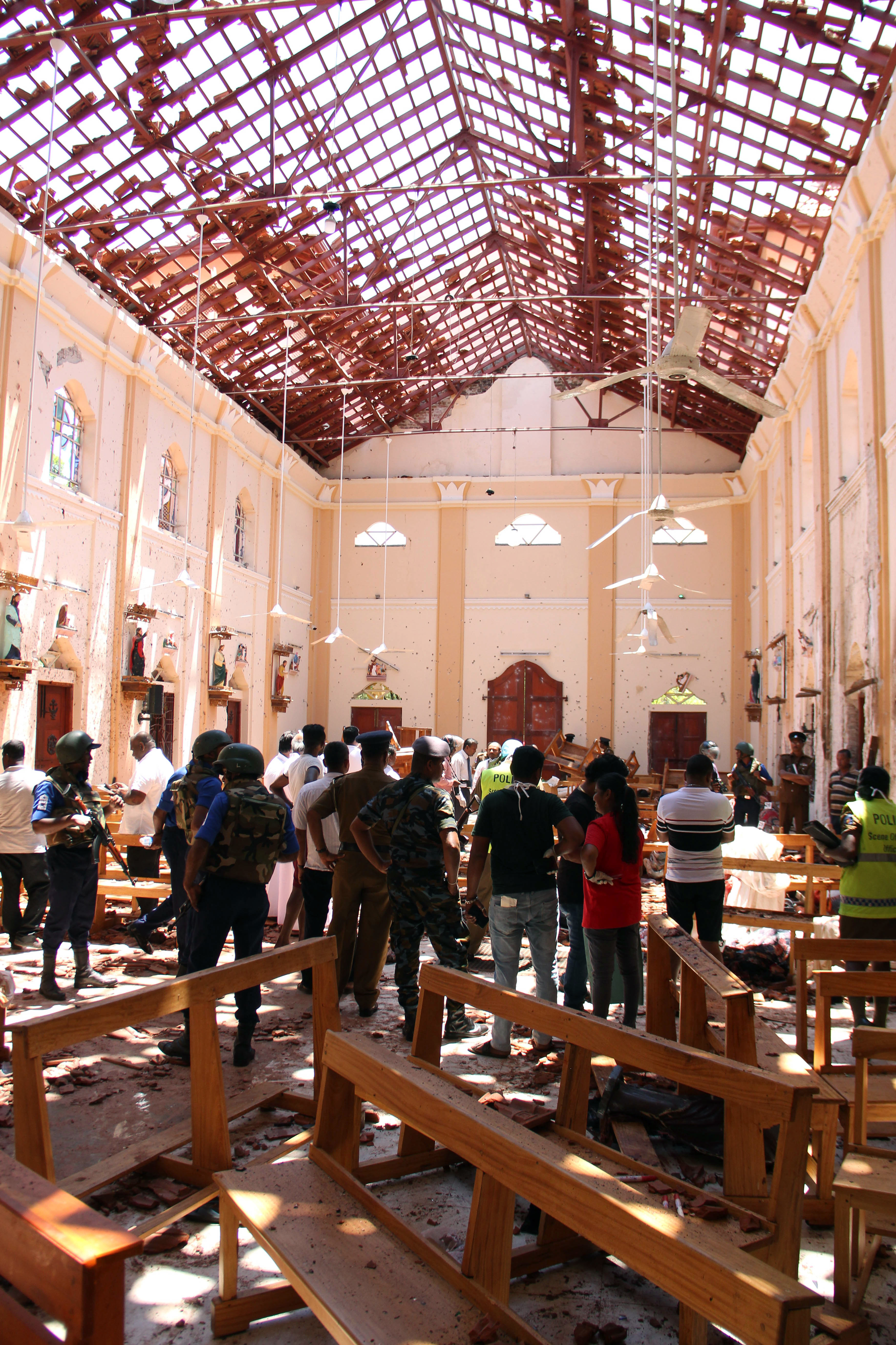 Sri Lankan security personnel walk through debris following an explosion in St Sebastian's Church in Negombo, north of the capital Colombo, on April 21, 2019. - A series of eight devastating bomb blasts ripped through high-end hotels and churches holding Easter services in Sri Lanka on April 21, killing nearly 160 people, including dozens of foreigners. (Photo by STR / AFP) sri lanka bombing