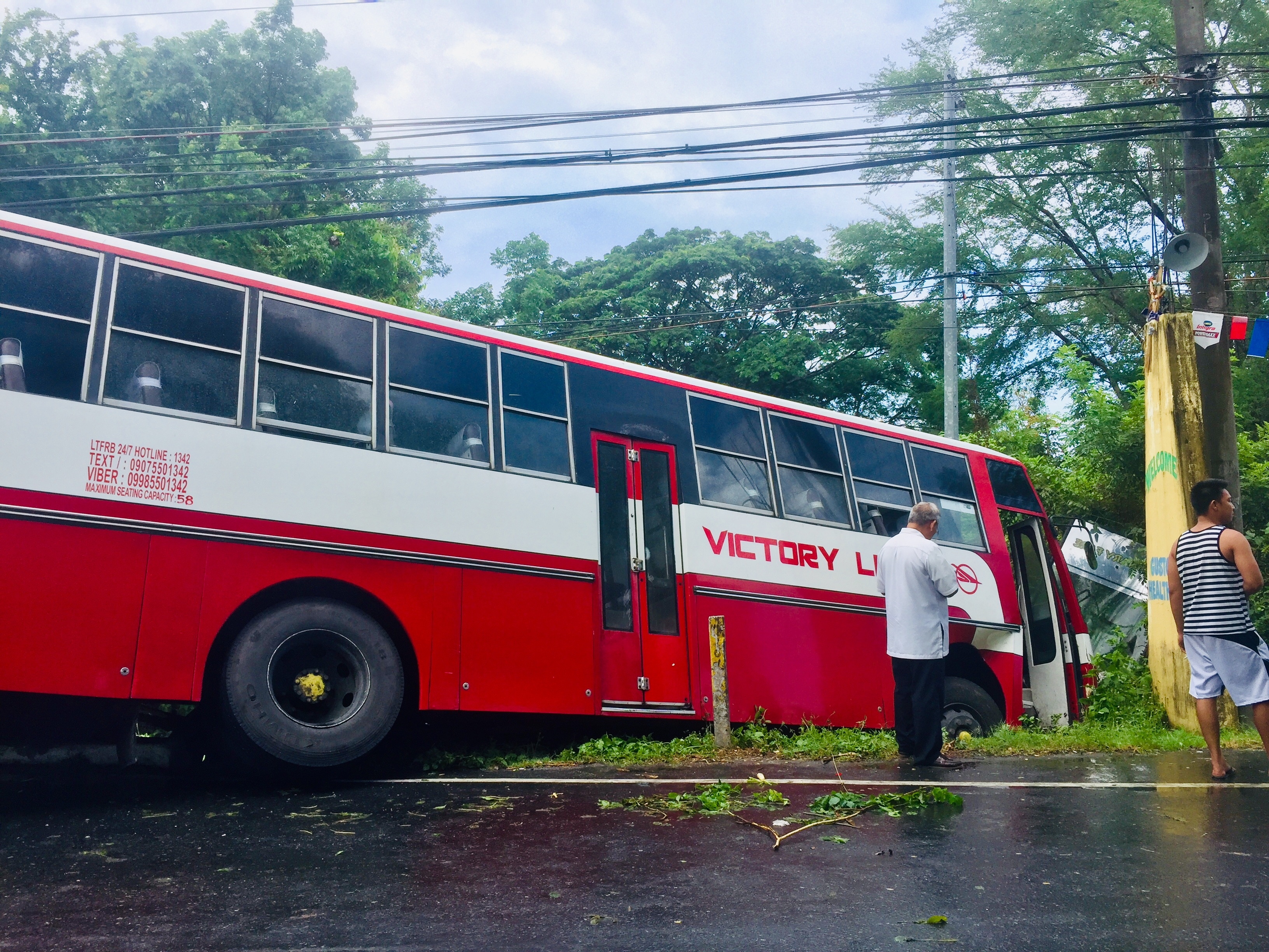 A slippery road caused this passenger bus to swerve and fall into the road gutter along the National Road in Barangay Antipolo, San Antonio, Zambales, injuring the driver and 19 passengers on Saturday. (Photo by Joanna Rose Aglibot)
