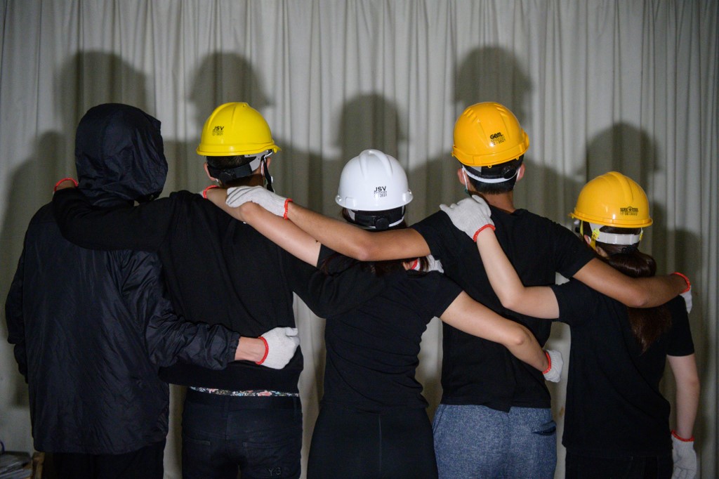 This picture taken on June 14, 2019, shows a group of student protesters posing while wearing their protective clothing during an interview with AFP in Hong Kong, who took part in the protests on June 12, which saw police armed with tear gas and rubber bullets. - Hong Kong's tech-savvy protesters are going digitally dark as they try to avoid surveillance and potential future prosecutions, disabling location tracking on their phones, buying train tickets with cash and purging their social media conversations. (Photo by Anthony WALLACE / AFP)