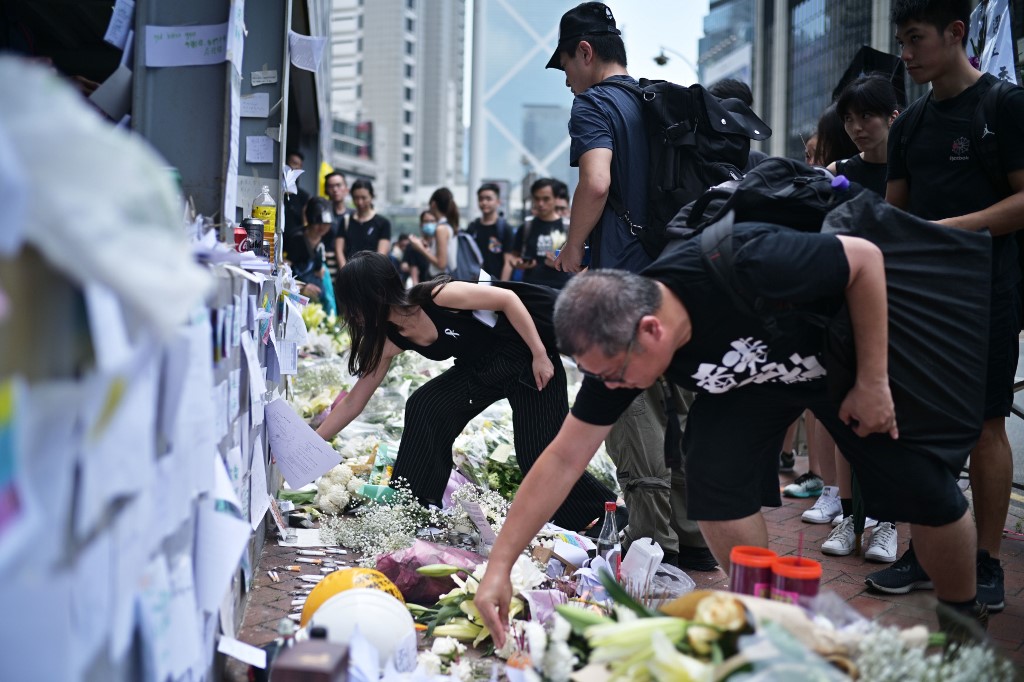 Mourners place flowers and offer prayers at the site where a protester died, prior to the start of a rally in Hong Kong on June 16, 2019. - Hong Kong was braced for another mass rally, as public anger seethed following unprecedented clashes between protesters and police over an extradition law, despite a climbdown by the city's embattled leader in suspending the bill. Nearly 80 people were injured in this week's unrest, including 22 police officers, and one man died late on June 15, 2019 when he fell from a building where he had been holding an hours-long anti-extradition protest. (Photo by Anthony WALLACE / AFP)