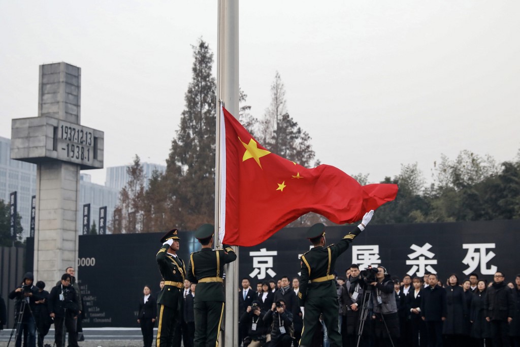 People's Liberation Army (PLA) soldiers raise the Chinese flag during a memorial ceremony at the Nanjing Massacre Memorial Hall on the annual national day of remembrance to commemorate the 81st anniversary of the massacre in Nanjing in China's eastern Jiangsu province on December 13, 2018. (Photo by STR / AFP) / China OUT 