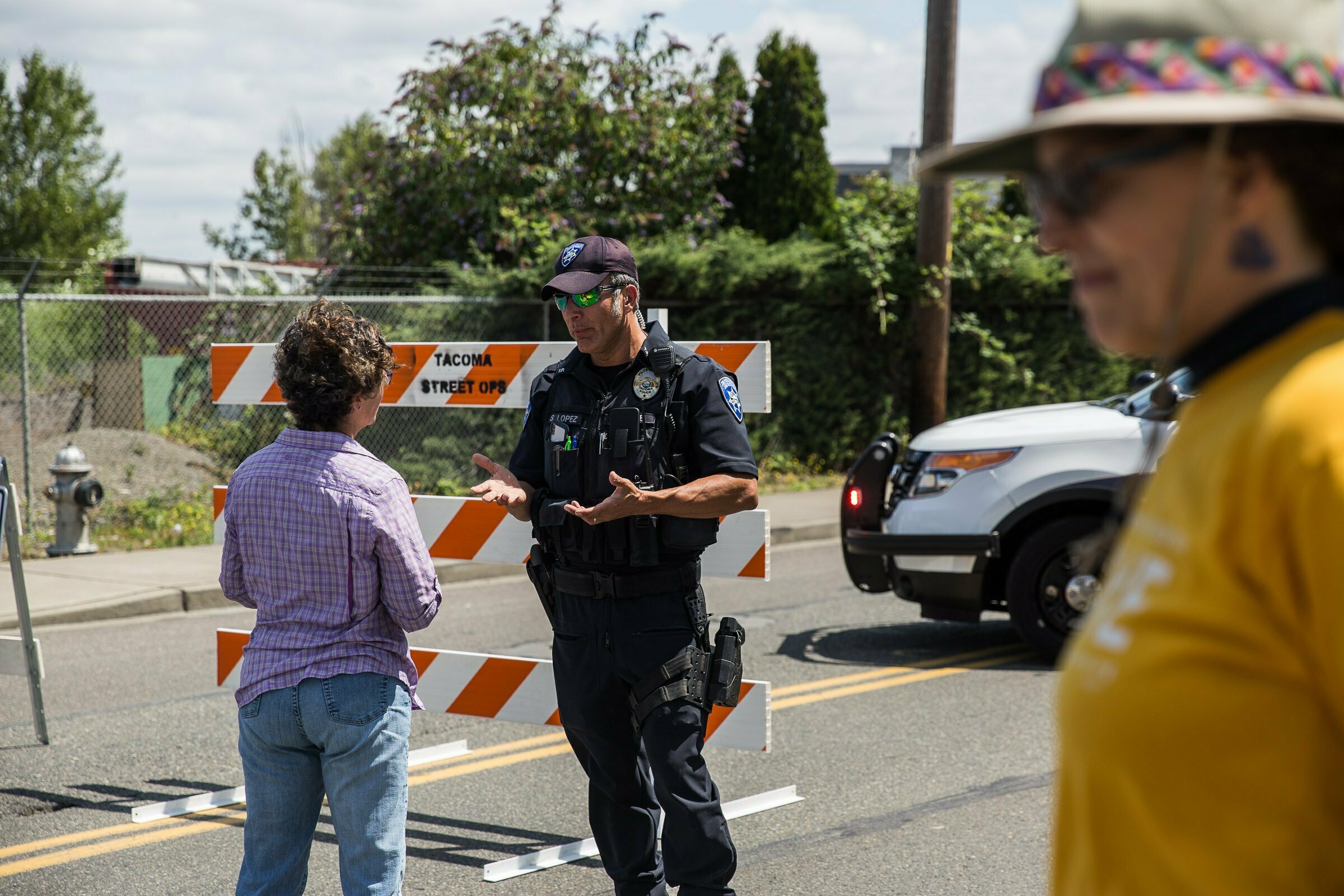 Police Officer Sam Lopez turns away would-be protesters in front of a road block near the Northwest Detention Center, Saturday July 13, 2019 in Tacoma, Wash. A man armed with a rifle threw incendiary devices at an immigration jail in Washington state early Saturday morning, then was found dead after four police officers arrived and opened fire, authorities said. (Rebekah Welch/The Seattle Times via AP)