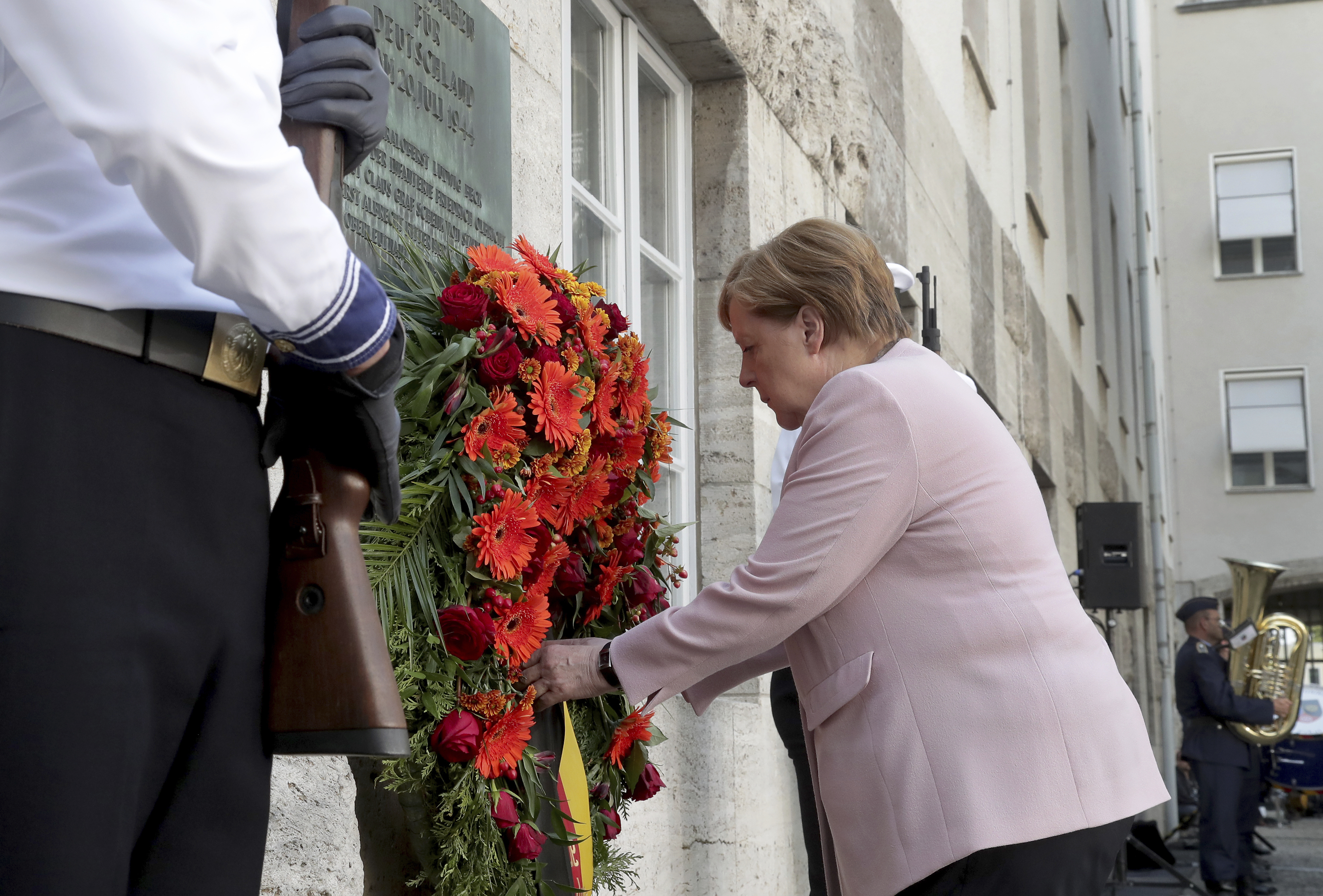 German Chancellor Angela Merkel adjusts a wreath during a memorial event at the Defence Ministry in Berlin, Germany, Saturday, July 20, 2019. On July 20, 2019 Germany marks the 75th anniversary of the failed attempt to kill Hitler in 1944. (AP Photo/Michael Sohn)