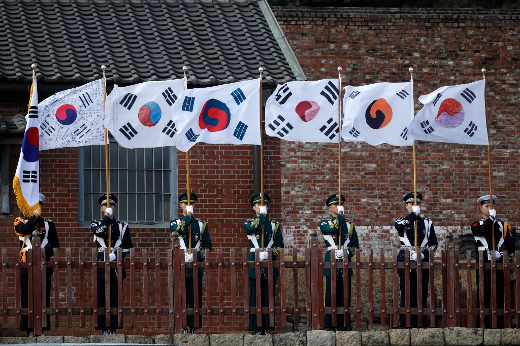 South Korean honour guards hold national flags during a ceremony celebrating the 99th anniversary of the March First Independence Movement against Japanese colonial rule at Seodaemun Prison History Hall in Seoul on March 1, 2018. - South Korean President Moon Jae-in on March 1 said Japan cannot declare the issue of its former wartime sex slaves "over", repeating calls for Tokyo to apologise over the issue and confront wrongdoings. (Photo by KIM HONG-JI / POOL / AFP)