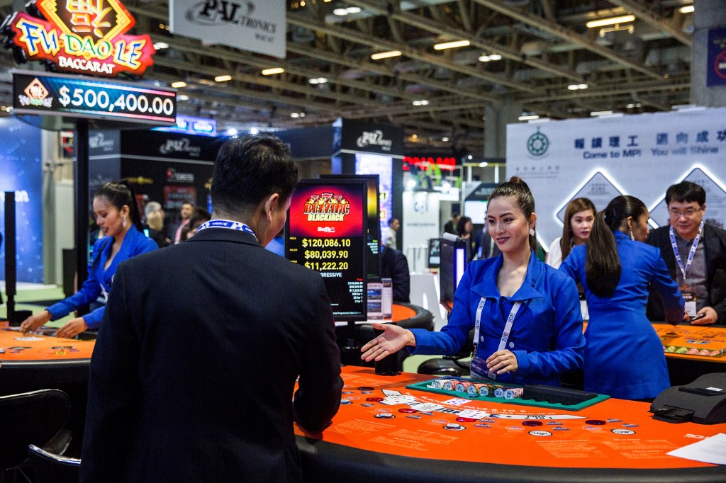 A visitor (L) watches a card dealer demonstrating a game at the Global Gaming Expo in Macau on May 21, 2019. (Photo by Isaac LAWRENCE / AFP)