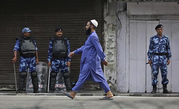 Muslim man walks in front of Indian troops