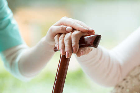 Young woman’s hand over an older man’s hands holding a cane. STORY: Congress will find funding for seniors’ pension hike – solon