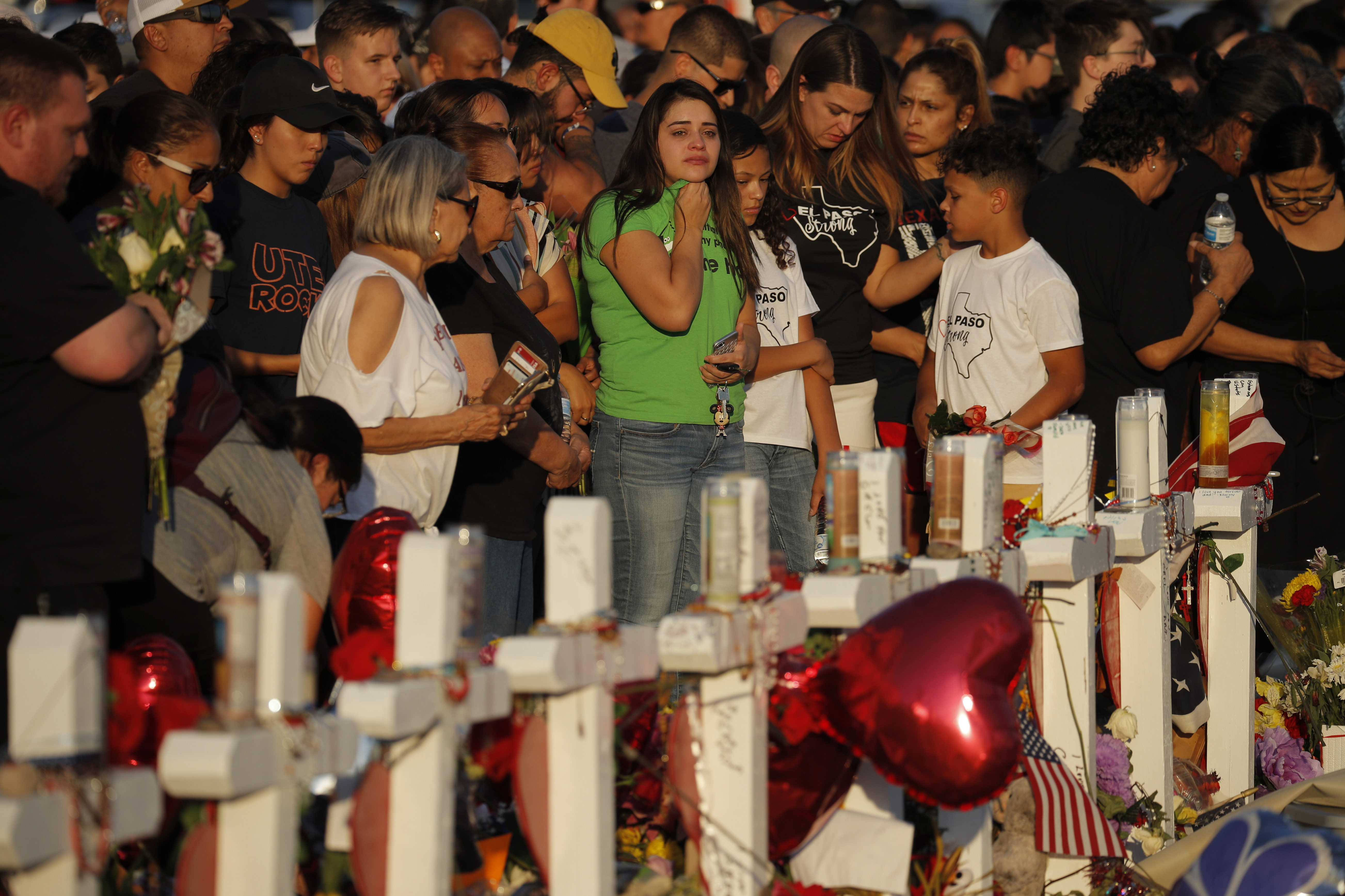 FILE - In this Aug. 6, 2019, file photo, people visit a makeshift memorial at the scene of a mass shooting at a shopping complex in El Paso, Texas. At the growing memorial for the victims of this Saturday massacre, the city’s roots in Catholicism and religion in general loom large. (AP Photo/John Locher, File)