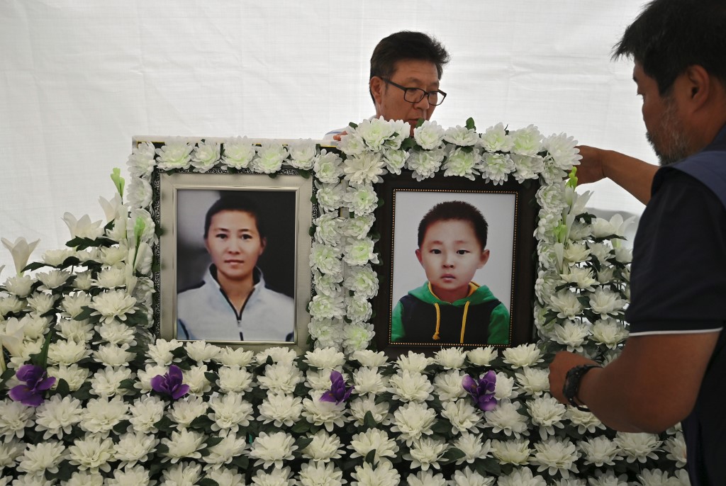 This picture taken on August 28, 2019 shows a man setting up portraits of late North Korean defector Han Sung-ok and her six-year-old son, who are believed to have died from starvation, at a makeshift shrine for Han and her son in downtown Seoul. - Han struggled to hold on to a job while caring for her son and the pair were found two months after their death in their apartment along with an empty bottle of soy sauce. (Photo by Jung Yeon-je / AFP) / TO GO WITH SKorea-NKorea-poverty-social,FOCUS  BY Sunghee Hwang
