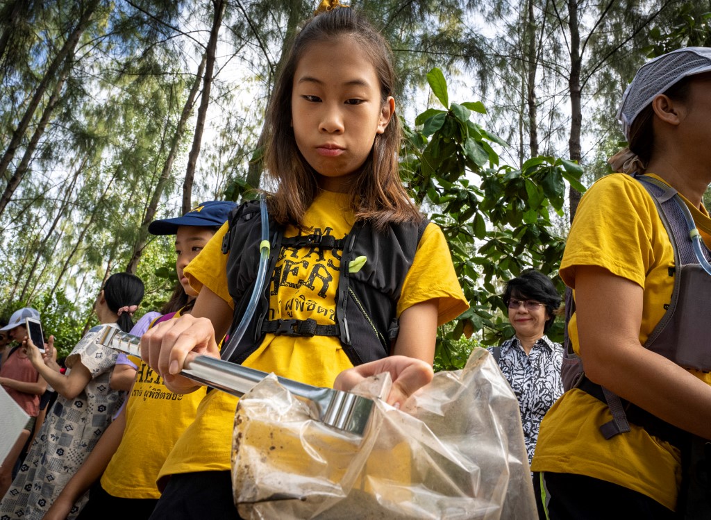 In this picture taken on August 25, 2019, 12-year-old Ralyn Satidtanasarn, known by her nickname Lilly, collects plastic waste during the Trash Hero cleaning initiative at the Khung Bang Kachao urban forest and beach in Bangkok. - Thailand is the sixth largest global contributor to ocean pollution, and plastic is a scourge. Whether its for wrapping up street food, takeaway coffees or for groceries, Thais use 3,000 single use bags per year -- 12 times more than someone from the European Union. (Photo by Mladen ANTONOV / AFP) / TO GO WITH Environment-plastic-Thailand-youth, FEATURE,FEATURE by Sophie DEVILLER