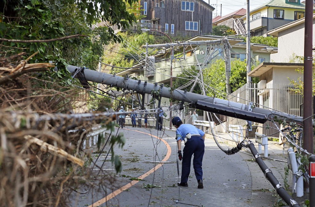 A police officer ispects a fallen utility pole downed by winds caused by Typhoon Faxai in Kamakura, Kanagawa prefecture on September 9, 2019. - The powerful typhoon that battered Tokyo overnight with ferocious winds killed two people, police said on September 9, as halted trains caused commuter chaos and more than 100 flights were cancelled. (Photo by jiji press / JIJI PRESS / AFP) / Japan OUT