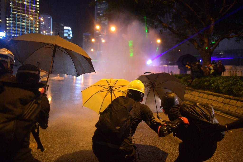 Protesters protect themselves after police fired water cannon toward them after the group occupied a main road in the Admiralty area in Hong Kong on September 28, 2019, on the fifth anniversary of the "Umbrella Movement". - Thousands of Hong Kongers gathered on September 28 to mark the fifth anniversary of the 'Umbrella Movement', the failed pro-democracy campaign that laid the groundwork for the massive protests currently engulfing the city. (Photo by Nicolas ASFOURI / AFP)