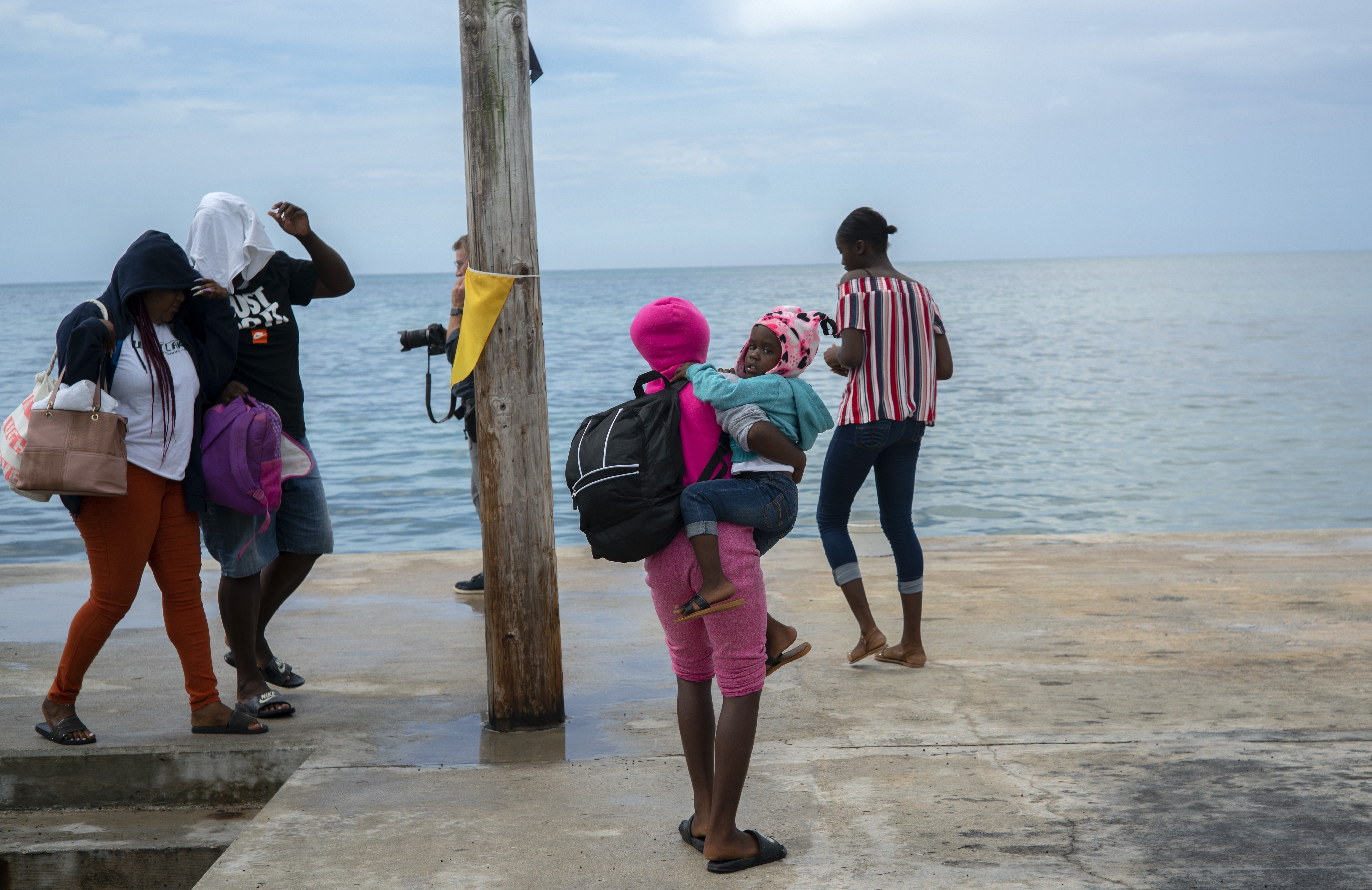 A woman carries a girl in her arms after being evacuated from a nearby Cay due to the danger of floods after arrive on a ship at the port before the arrival of Hurricane Dorian in Sweeting's Cay, Grand Bahama, Bahamas, Saturday Aug. 31, 2019.   Dorian bore down on the Bahamas as a fierce Category 4 storm Saturday, with new projections showing it curving upward enough to potentially spare Florida a direct hit but still threatening parts of the Southeast U.S. with powerful winds and rising ocean water that causes what can be deadly flooding. (AP Photo/Ramon Espinosa)