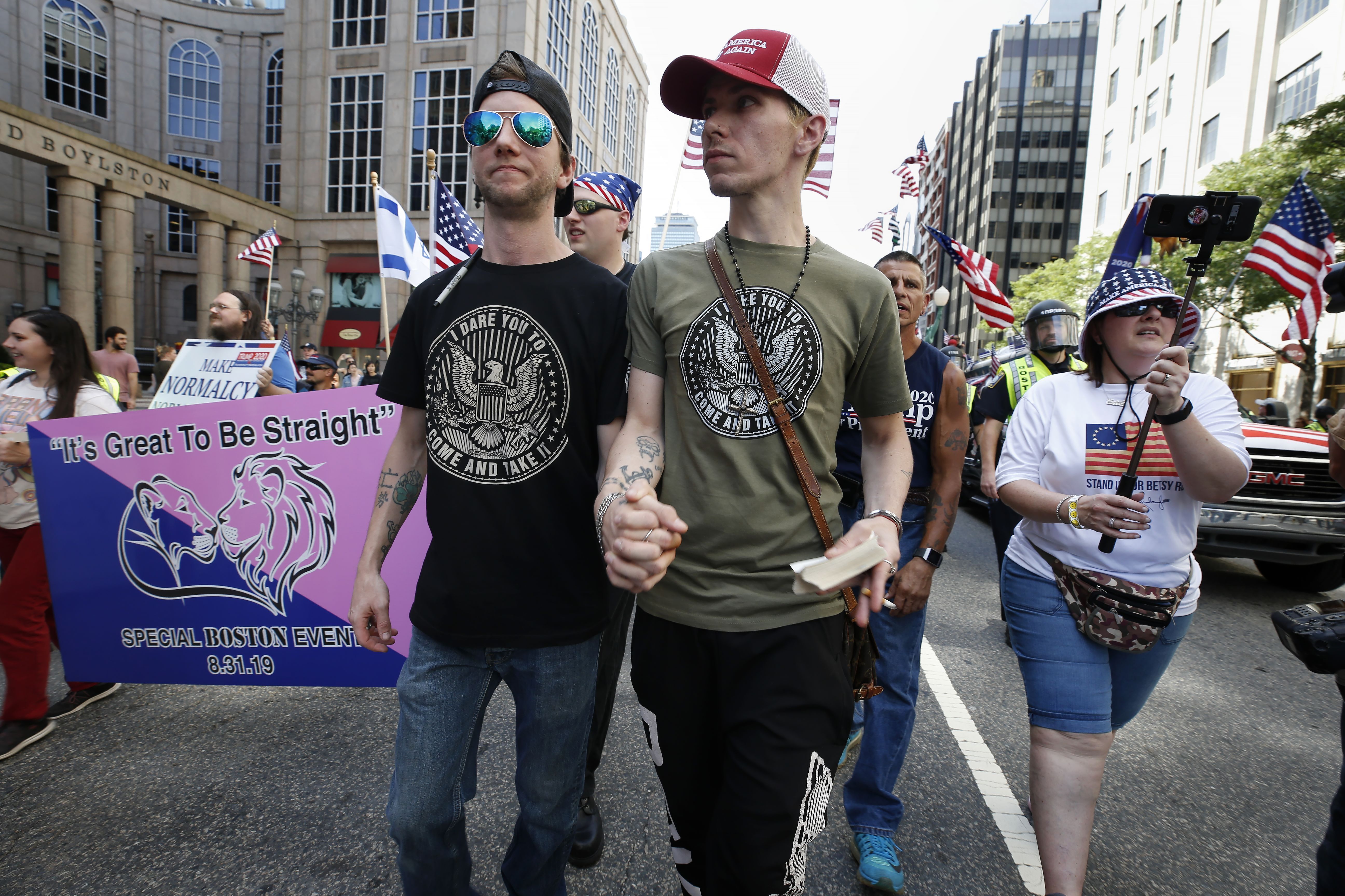 Peter Brown, center left, and Mark Hutt, center right, who said they are engaged to be married, hold hands as they march with others in the Straight Pride Parade in Boston, Saturday, Aug. 31, 2019. (AP Photo/Michael Dwyer)