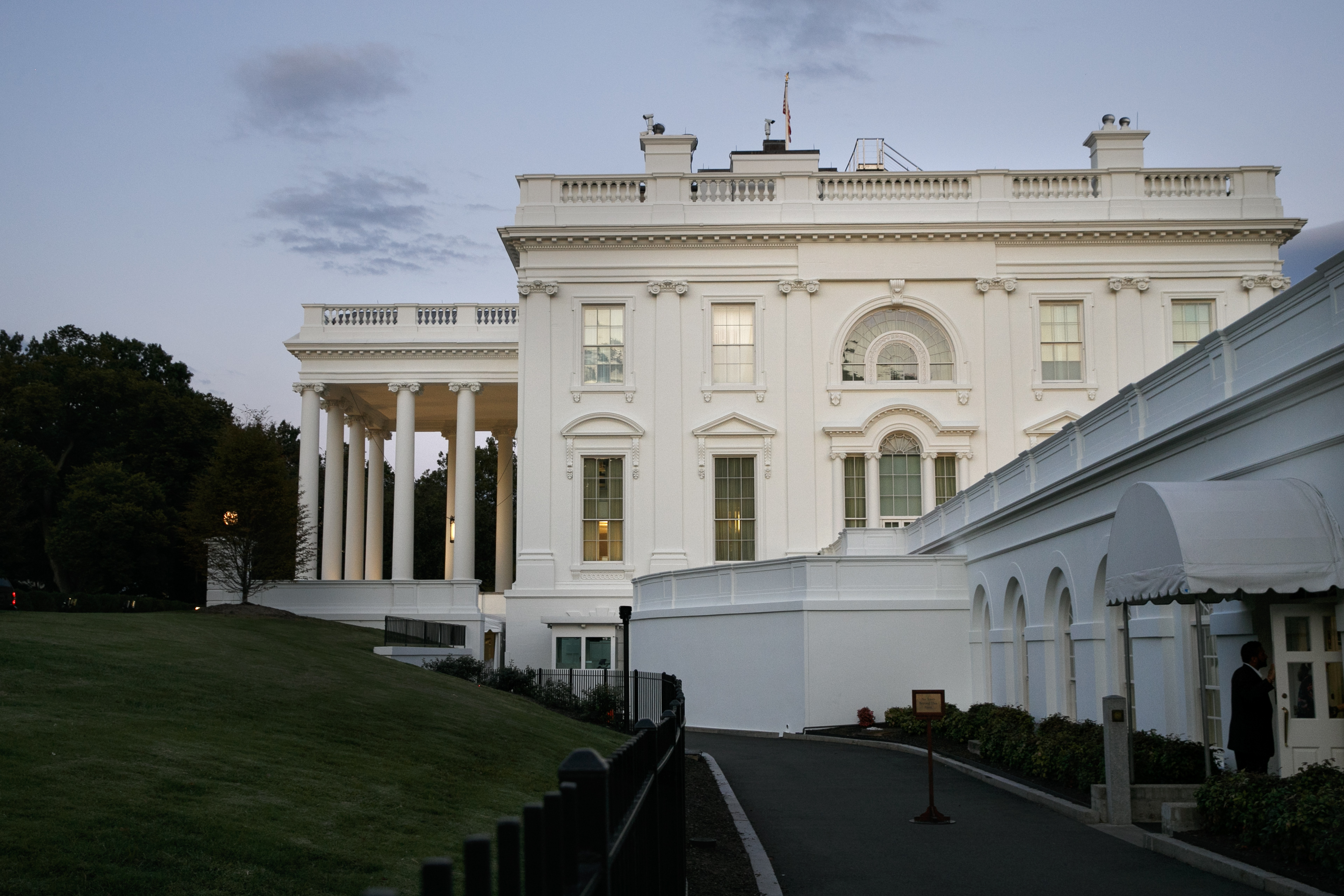 A man enters the press area of the White House at dusk, Saturday, Sept. 7, 2019, in Washington. On Saturday, Sept. 7, 2019, President Donald Trump tweeted he has called off a secret Camp David meeting with Taliban and Afghanistan leaders. (AP Photo/Jacquelyn Martin)