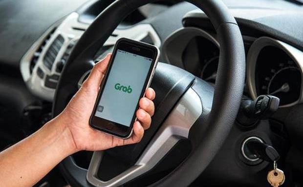 PHOTO: Stock image of man olding a cellphone with the Grab logo showing on the screen. STORY: Marcos cites TNVS firm’s role in employment growth