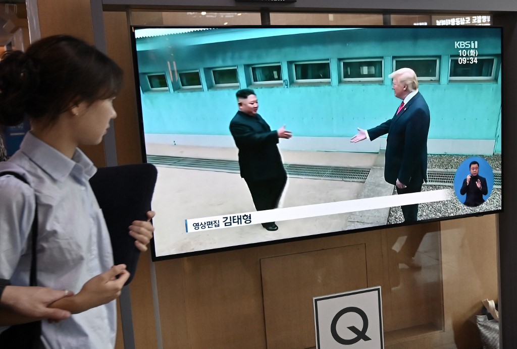 A woman walks past a television news screen showing file footage of a meeting between US President Donald Trump and North Korean leader Kim Jong Un at the truce village of Panmunjom, at a railway station in Seoul on September 10, 2019. - North Korea on September 10 fired projectiles toward the sea, South Korea's military said, hours after Pyongyang said it is willing to hold working-level talks with the United States in late September. (Photo by Jung Yeon-je / AFP)