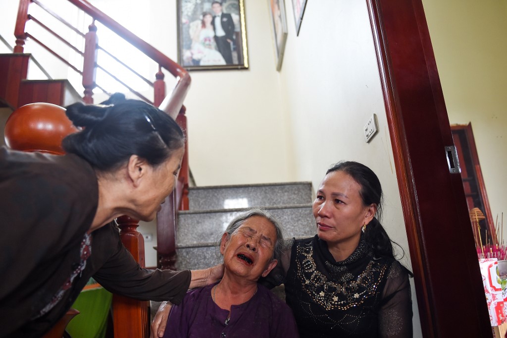 Tran Thi Hue (C), grandmother of 30-year old Le Van Ha, who is feared to be among the 39 people found dead in a truck in Britain, is consoled by relatives inside their house in Vietnam's Nghe An province on October 27, 2019. (Photo by NHAC NGUYEN / AFP)