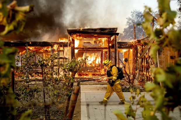 California firefighter walking past burning house