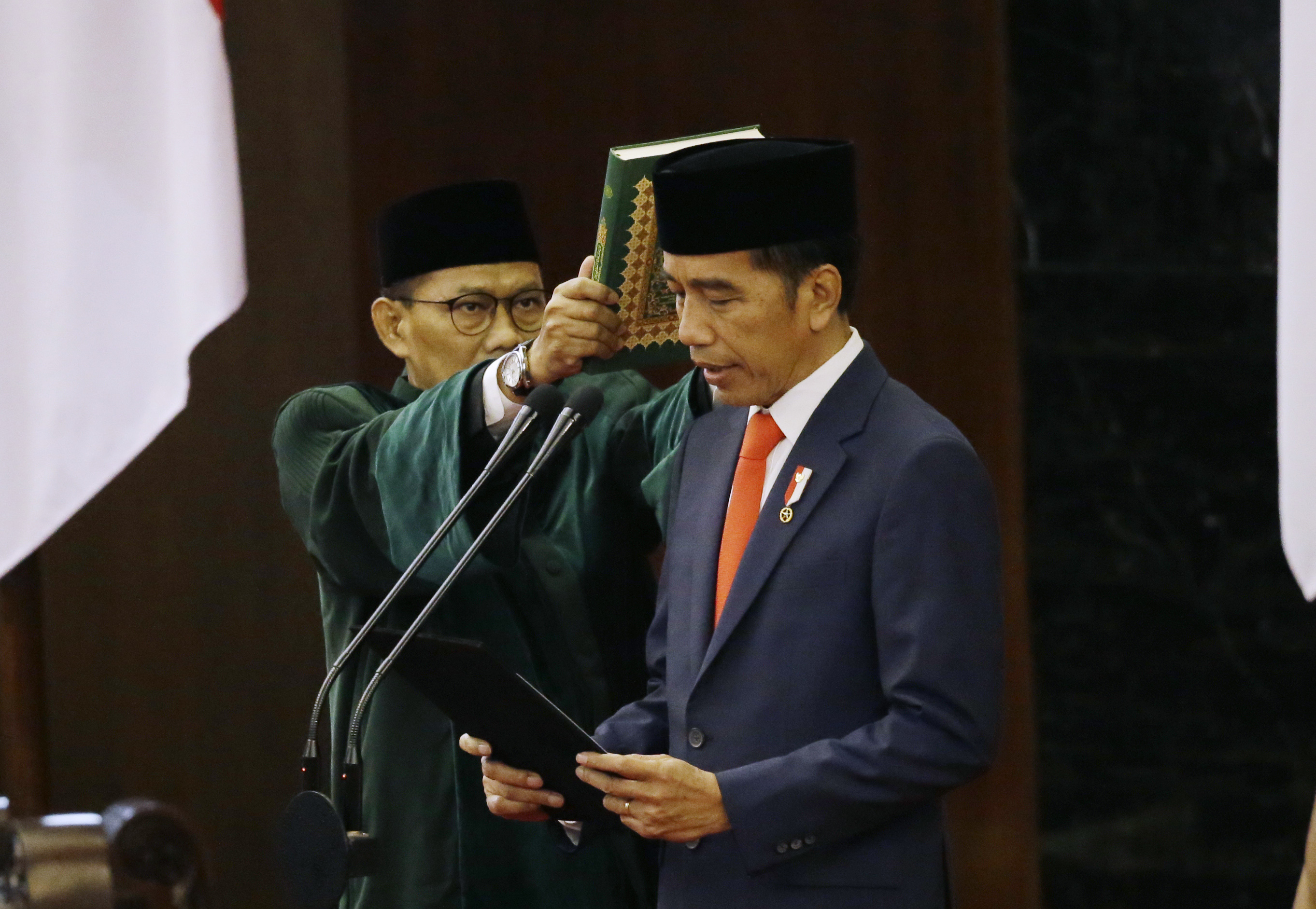 Indonesian President Joko Widodo, right, reads his oath during his inauguration ceremony as the country's seventh president at the parliament building in Jakarta, Indonesia Sunday, Oct. 20, 2019. Widodo, who rose from poverty and pledged to champion democracy, fight entrenched corruption and modernize the world's most populous Muslim-majority nation, was sworn in Sunday for his second and final five-year term with a pledge to take bolder actions. (AP Photo/Achmad Ibrahim, Pool)