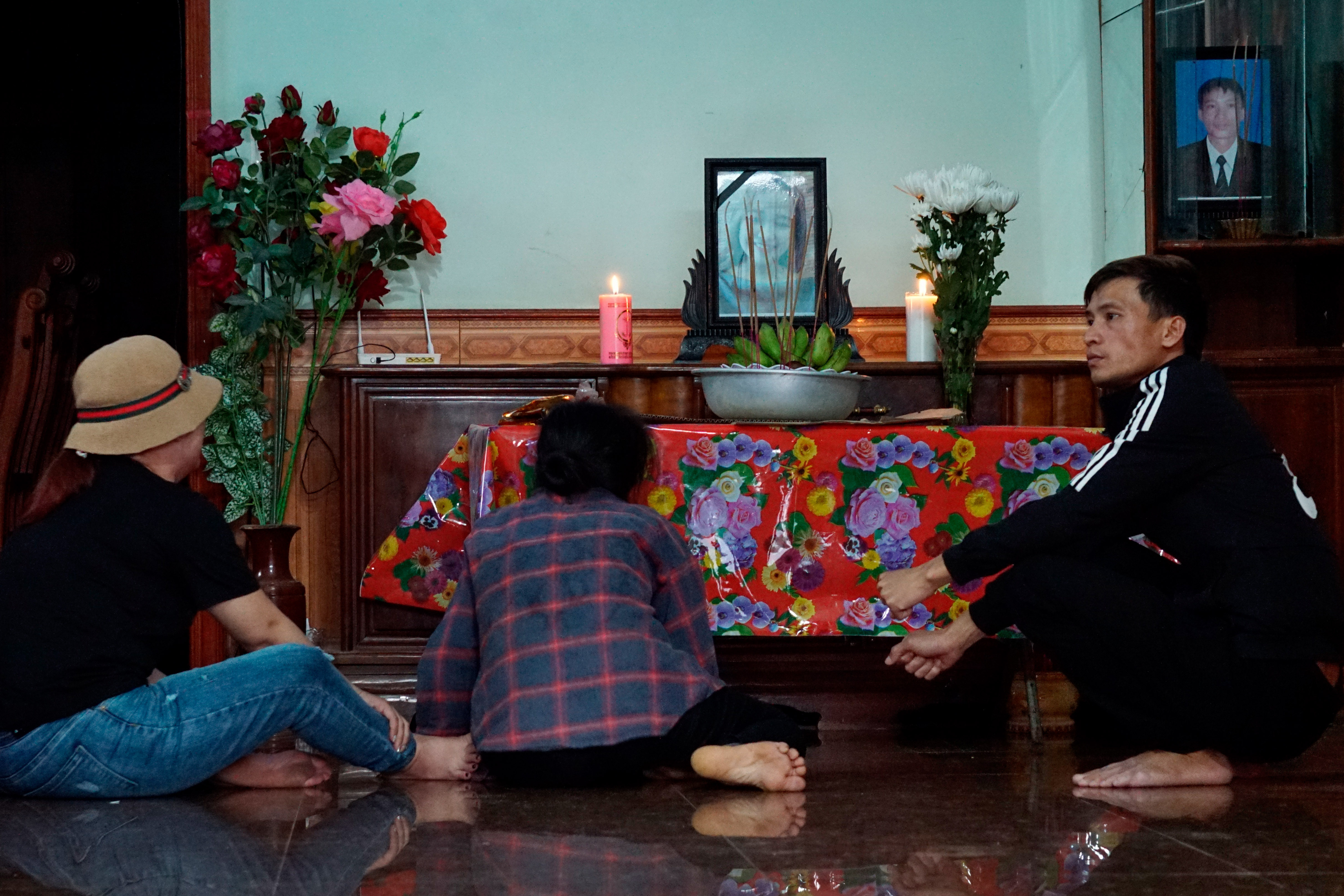 The mother, center, and other relatives of Bui Thi Nhung sit in front of an altar with Nhung's portrait inside her home Saturday, Oct. 26, 2019 in Do Thanh village, Nghe An province, Vietnam. Family members fear that Nhung could be among the dozens of people found dead in the back of a truck in England. (AP Photo/Linh Do)