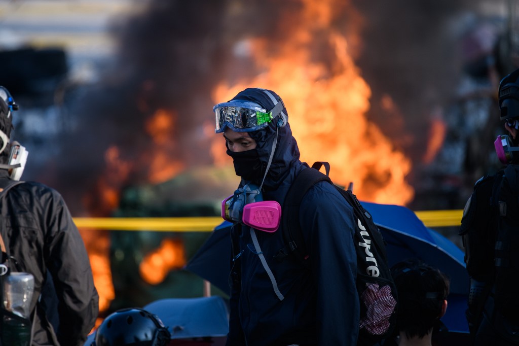 Protesters stand in front of a burning barricade at the Chinese University of Hong Kong (CUHK), in Hong Kong early on November 13, 2019. - Hong Kong pro-democracy protesters fought intense battles with riot police on a university campus and paralysed the city's upmarket business district Tuesday, extending one of the most violent stretches of unrest seen in more than five months of political chaos. (Photo by Anthony WALLACE / AFP)