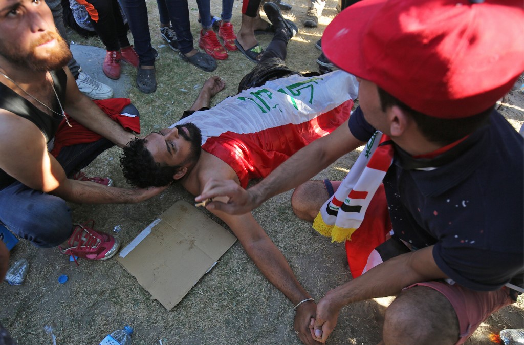 (FILES) In this file photo taken on October 04, 2019, Iraqi men try to help a wounded protester during a demonstration against state corruption, failing public services, and unemployment, in the Iraqi capital Baghdad's central Khellani Square. - At least 3,000 people who have been maimed in Baghdad and southern Iraq since anti-government protests erupted on October 1, according to the NGO Iraqi Alliance for Disabilities Organisation (IADO). After decades of back-to-back conflicts, Iraq is in the thick of its largest and deadliest grassroots protest movement, with more than 300 people dead and 15,000 wounded. (Photo by AHMAD AL-RUBAYE / AFP)