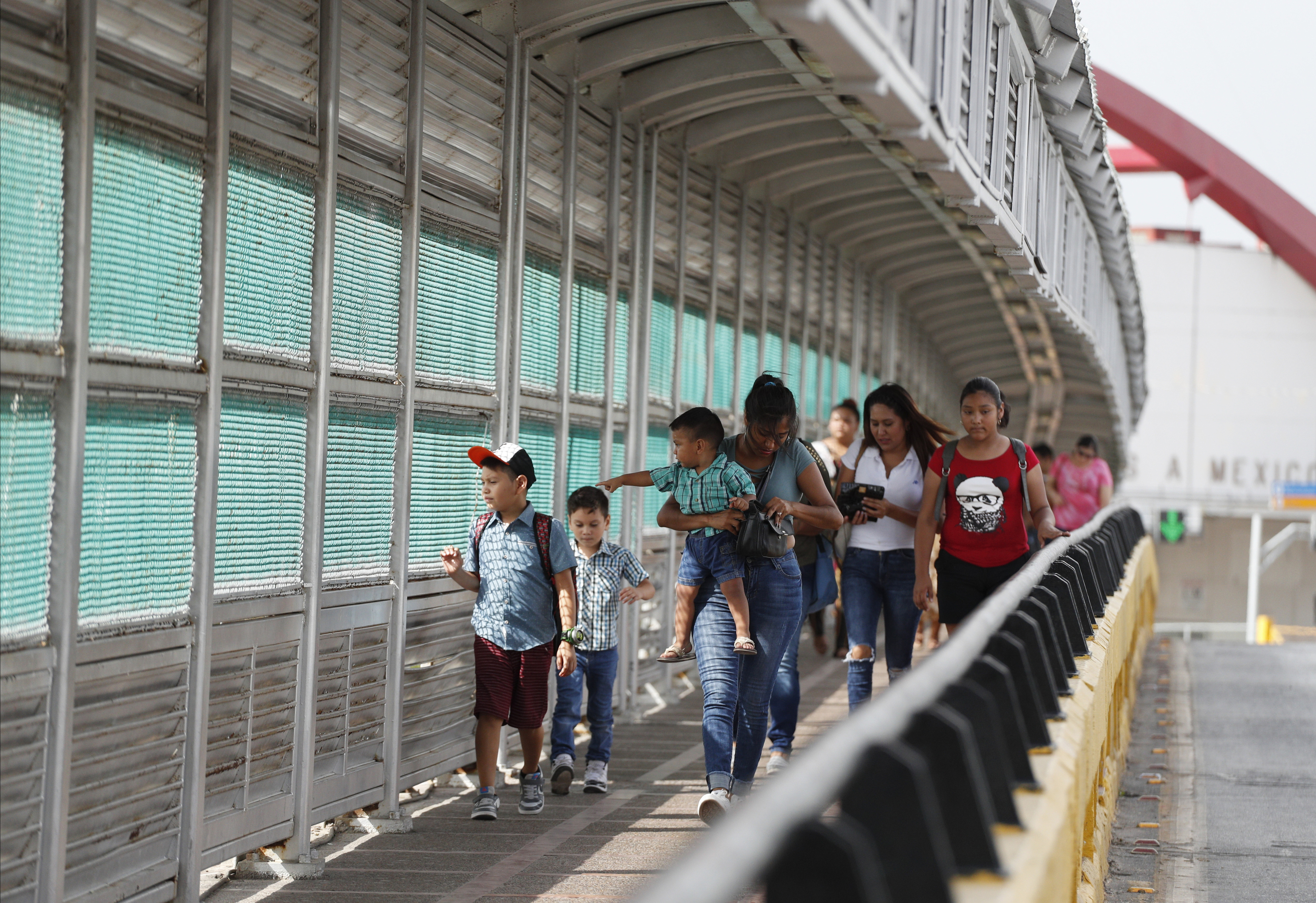 FILE - In this June 28, 2019 file photo, local residents with visas walk across the Puerta Mexico international bridge to enter the U.S., in Matamoros, Tamaulipas state, Mexico. A federal judge in Portland, Ore., on Saturday, Nov. 2, 2019, put on hold a Trump administration rule requiring immigrants prove they will have health insurance or can pay for medical care before they can get visas. U.S. District Judge Michael Simon granted a preliminary injunction that prevents the rule from going into effect Sunday. (AP Photo/Rebecca Blackwell, File)