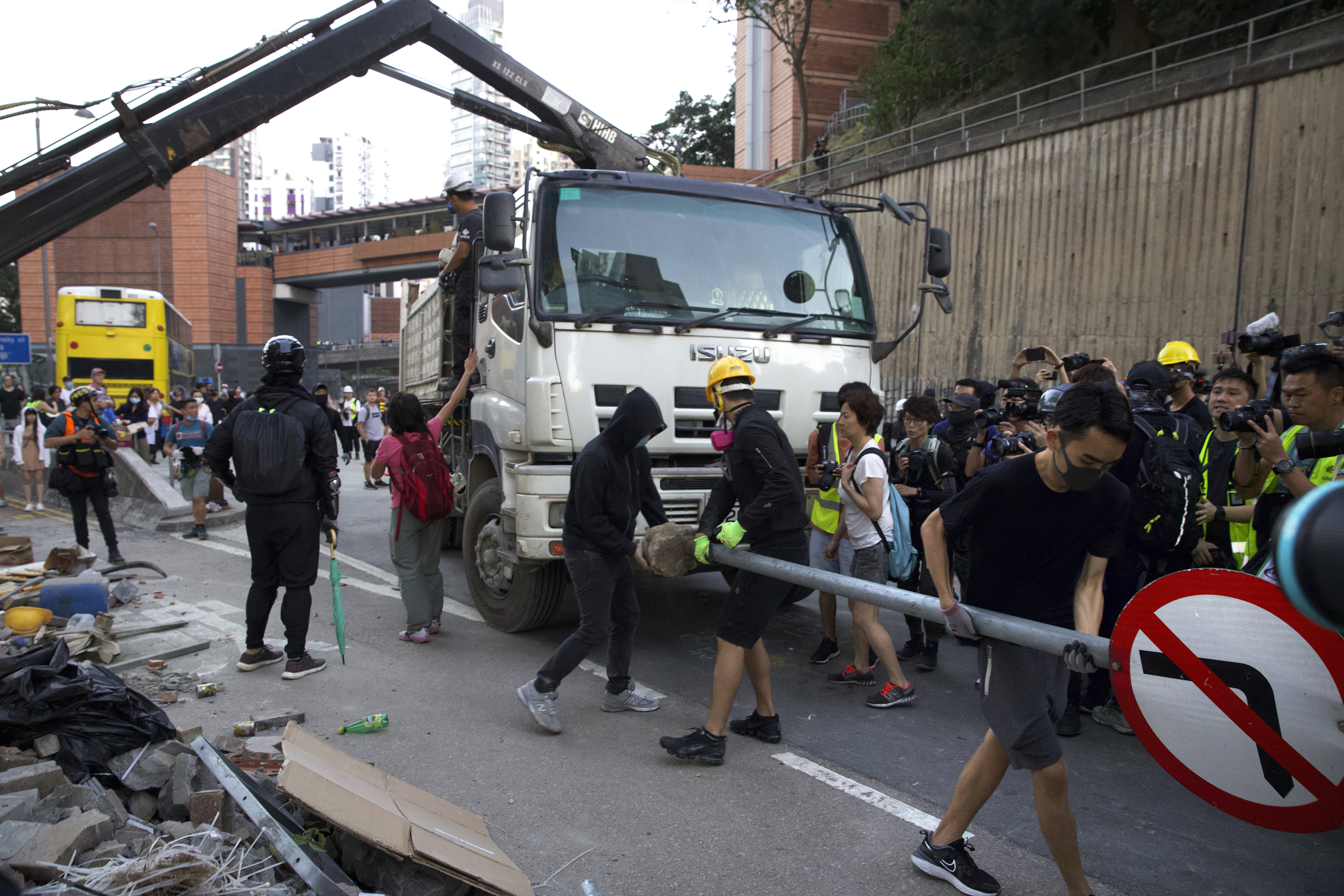 Protestors try to take back debris for road barricades that was cleared away by local residents near the University of Hong Kong in Hong Kong, Saturday, Nov. 16, 2019. Rebellious students and anti-government protesters abandoned their occupation of nearly all of Hong Kong's universities Saturday after a near weeklong siege by police, but at least one major campus remained under control of demonstrators. (AP Photo/Ng Han Guan)