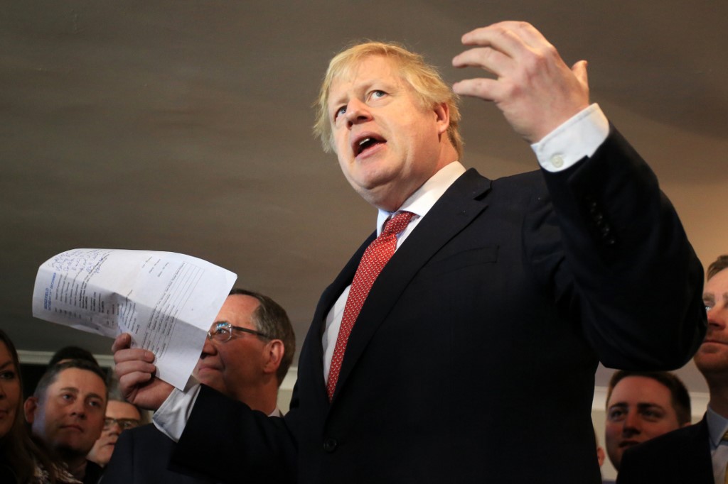 Britain's Prime Minister Boris Johnson gestures as he speaks to supporters on a visit to meet newly elected Conservative party MP for Sedgefield, Paul Howell at Sedgefield Cricket Club in County Durham, north east England on December 14, 2019, following his Conservative party's general election victory. - Prime Minister Boris Johnson called on Britons to put years of bitter divisions over the country's EU membership behind them as he vowed to use his resounding election victory to finally deliver Brexit next month. (Photo by Lindsey Parnaby / POOL / AFP)