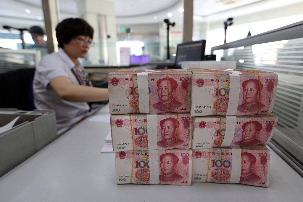Renminbi banknotes are placed on a bank staff's table in a bank in Lianyungang, east China's Jiangsu province on August 11, 2015. China's central bank on August 11 devalued its yuan currency by nearly two percent against the US dollar, as authorities seek to push market reforms and bolster the world's second-largest economy. CHINA OUT   AFP PHOTO (Photo by STR / AFP)